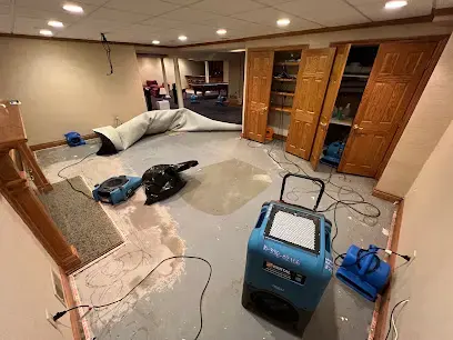 Dehumidifier and air movers drying a finished basement with the carpet pulled